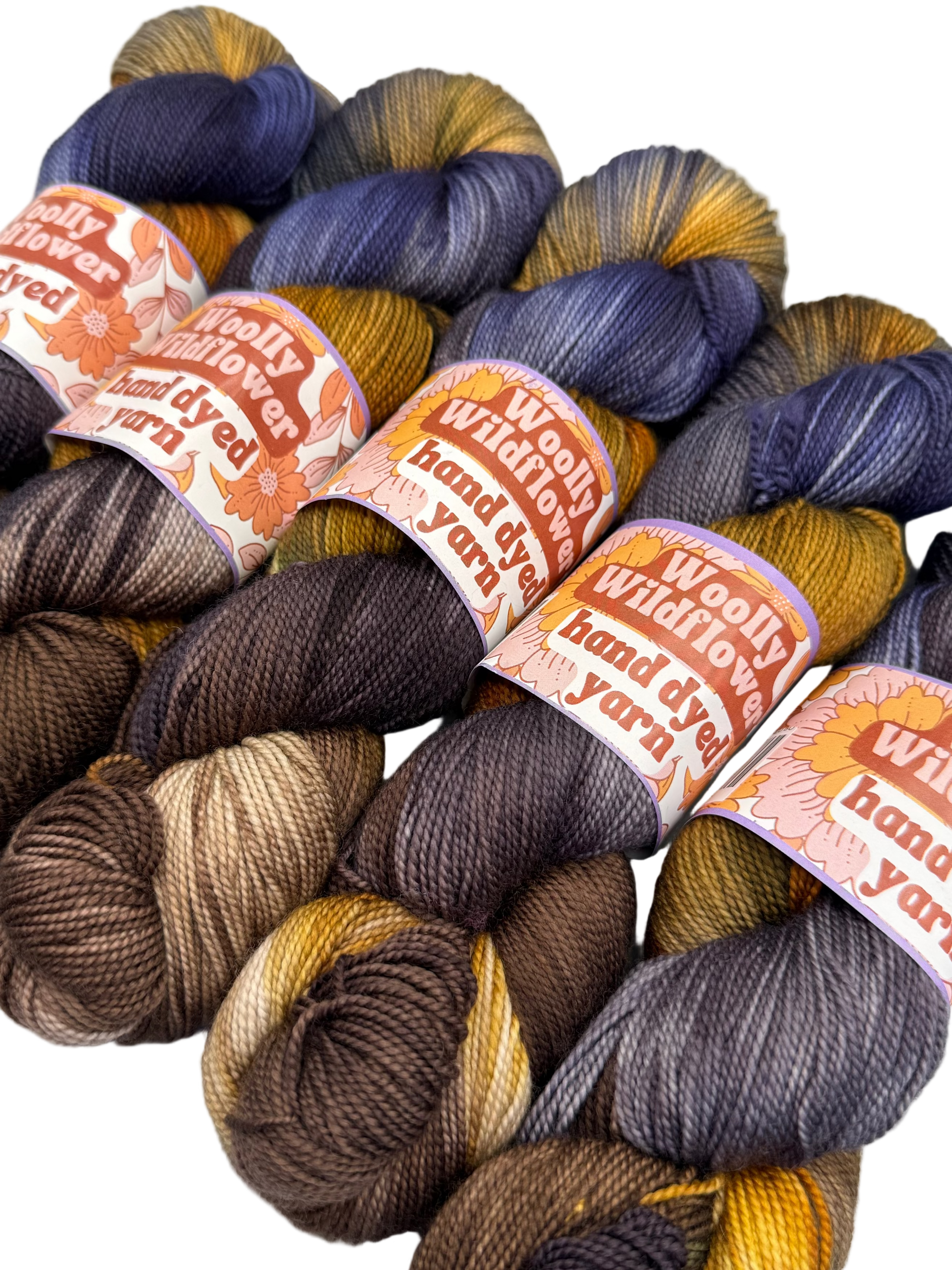 Woolly Wildflower hand-dyed yarn in various colors with labels.