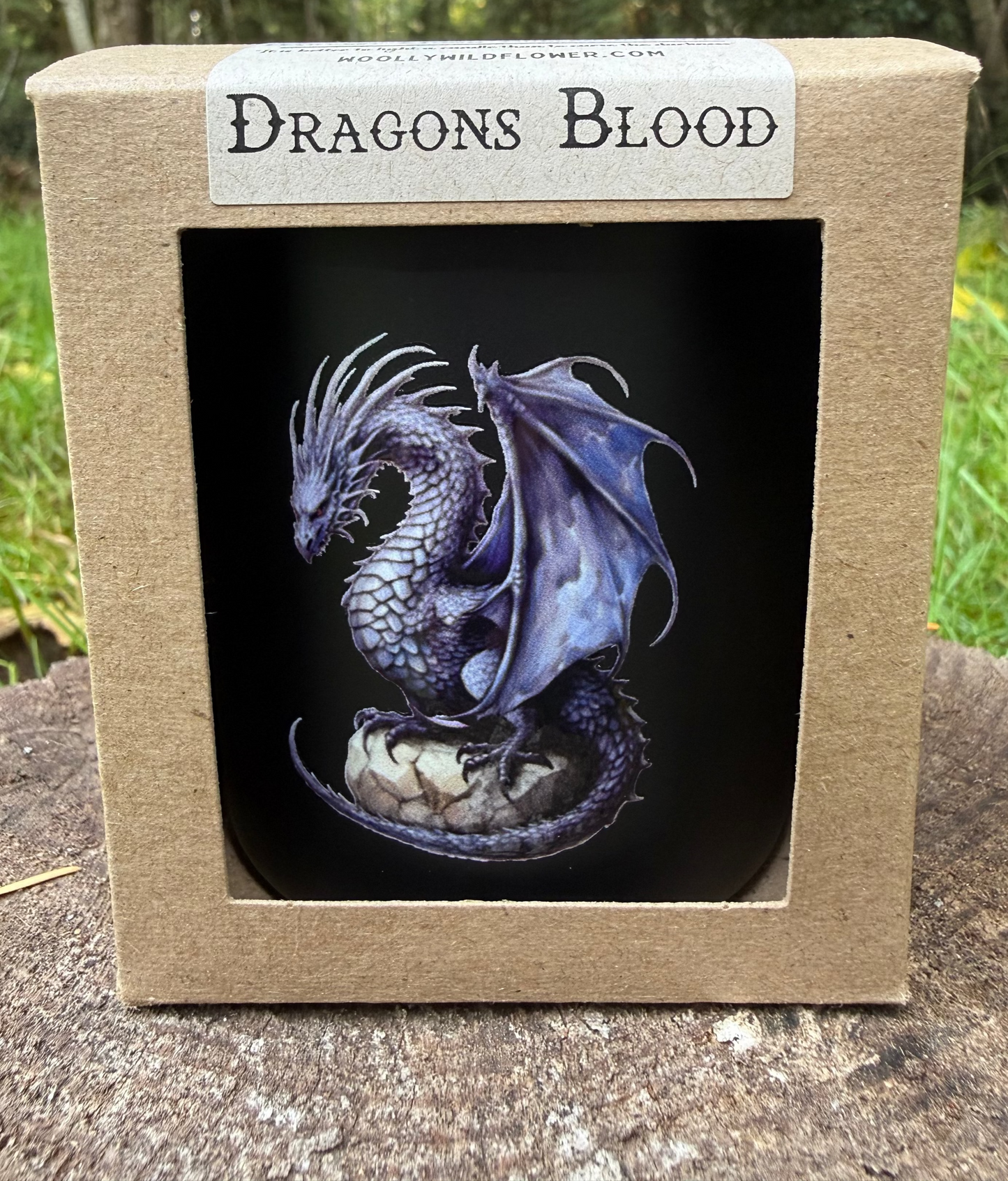 candle with dragon design in a box labeled 'Dragon's Blood' outdoors.