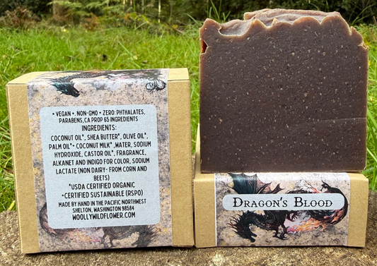 Bar of soap labeled 'Dragon's Blood' with packaging on a stone surface outdoors.