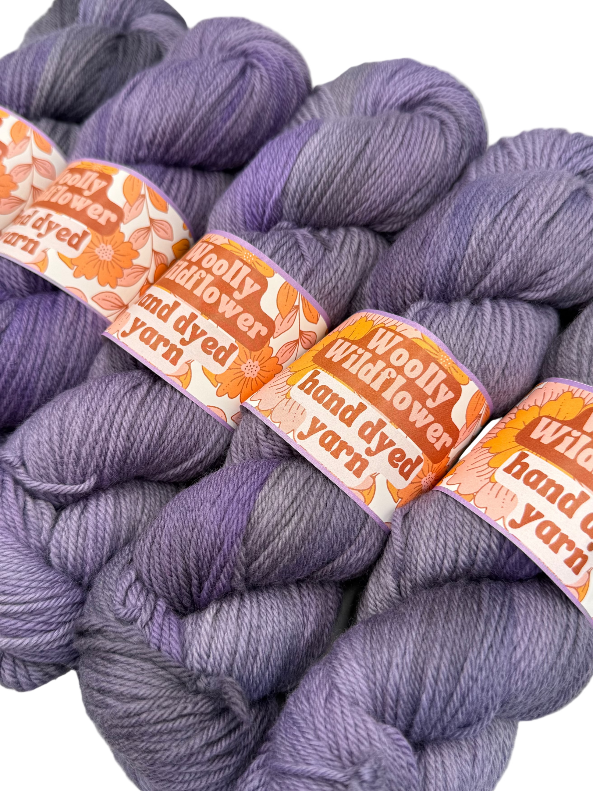 Bundles of purple yarn with 'Woolly Wildflower' labels on a white background
