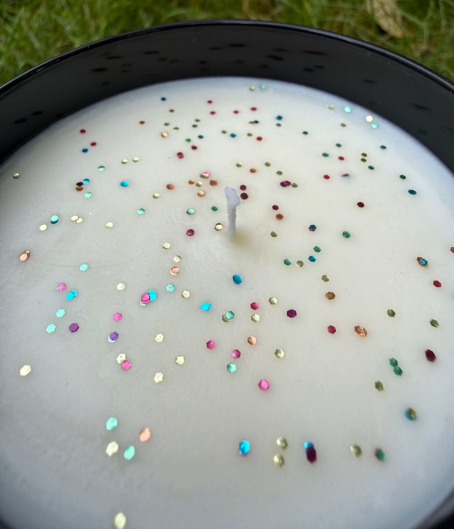 Candle with colorful sprinkles on a grassy background