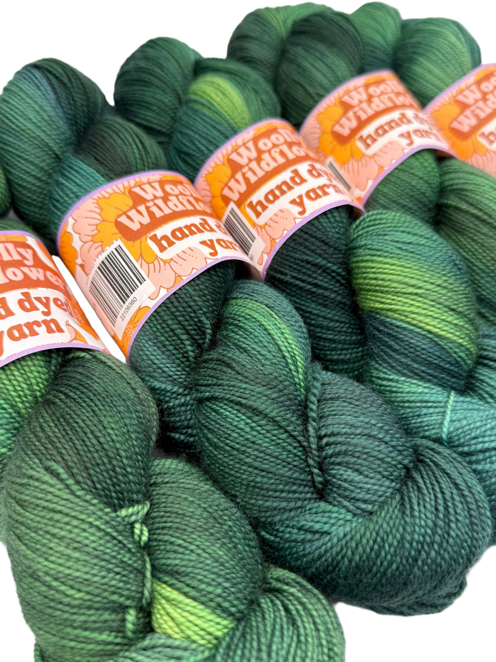 Green yarn skeins with 'Woolly Wildflower' labels on a white background