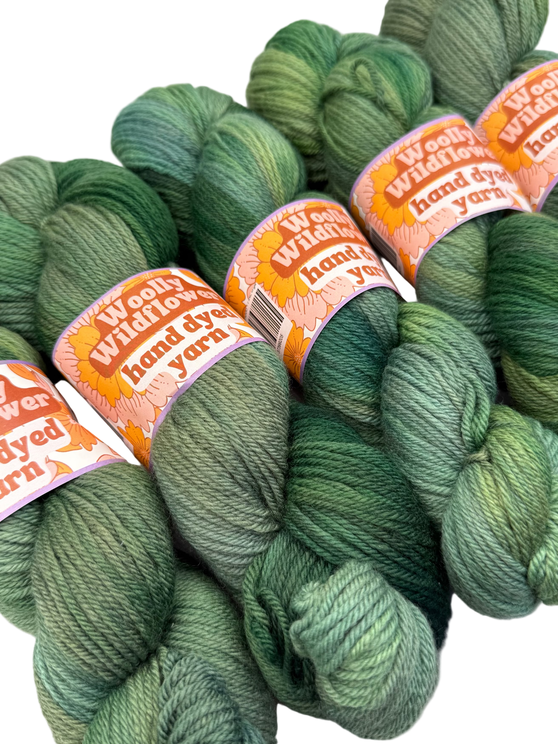 Green yarn skeins with 'Woolly Wormhead' labels on a white background