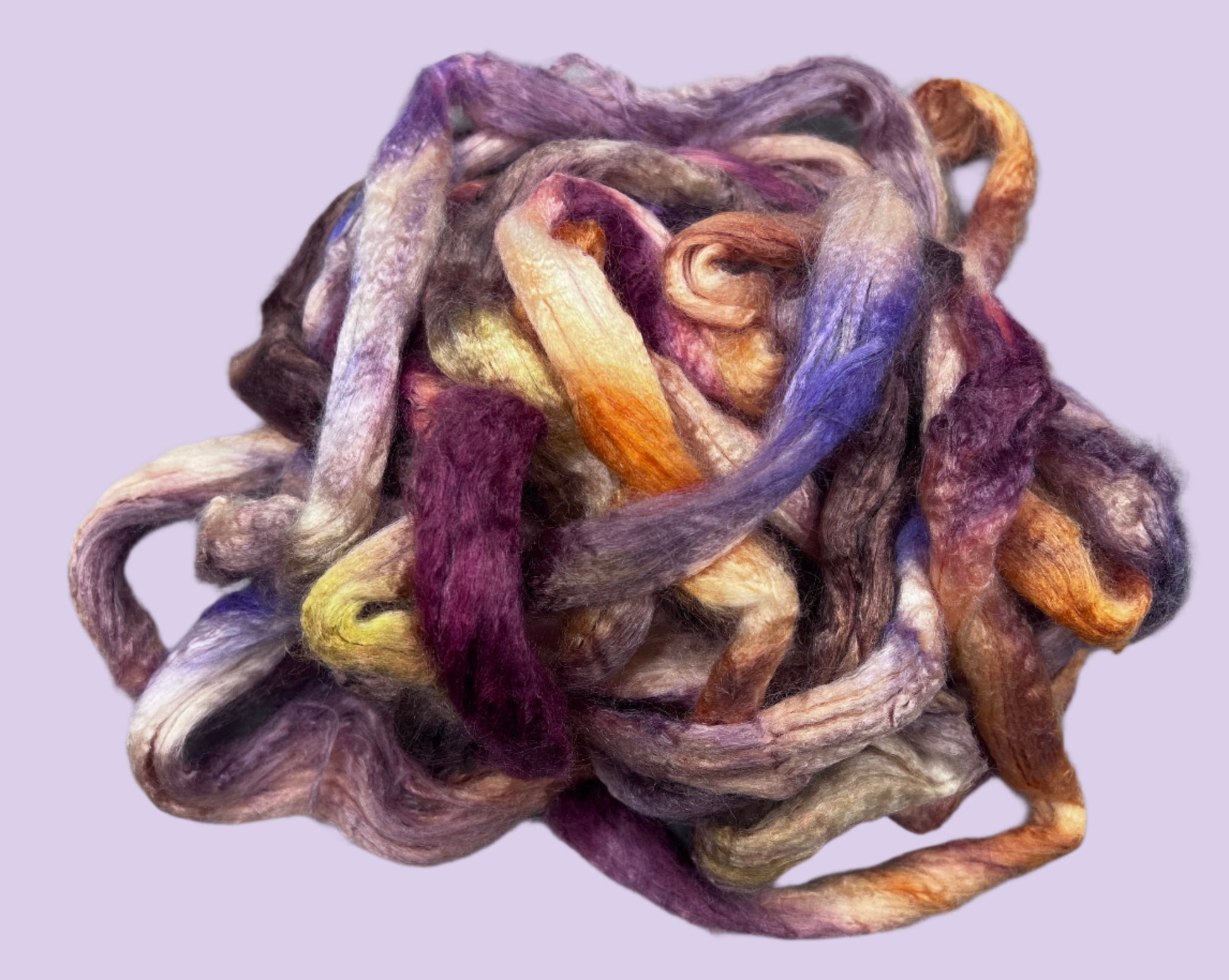A bundle of Tussah silk fibers in various shades including purple, red, orange, and brown, twisted and clumped together.