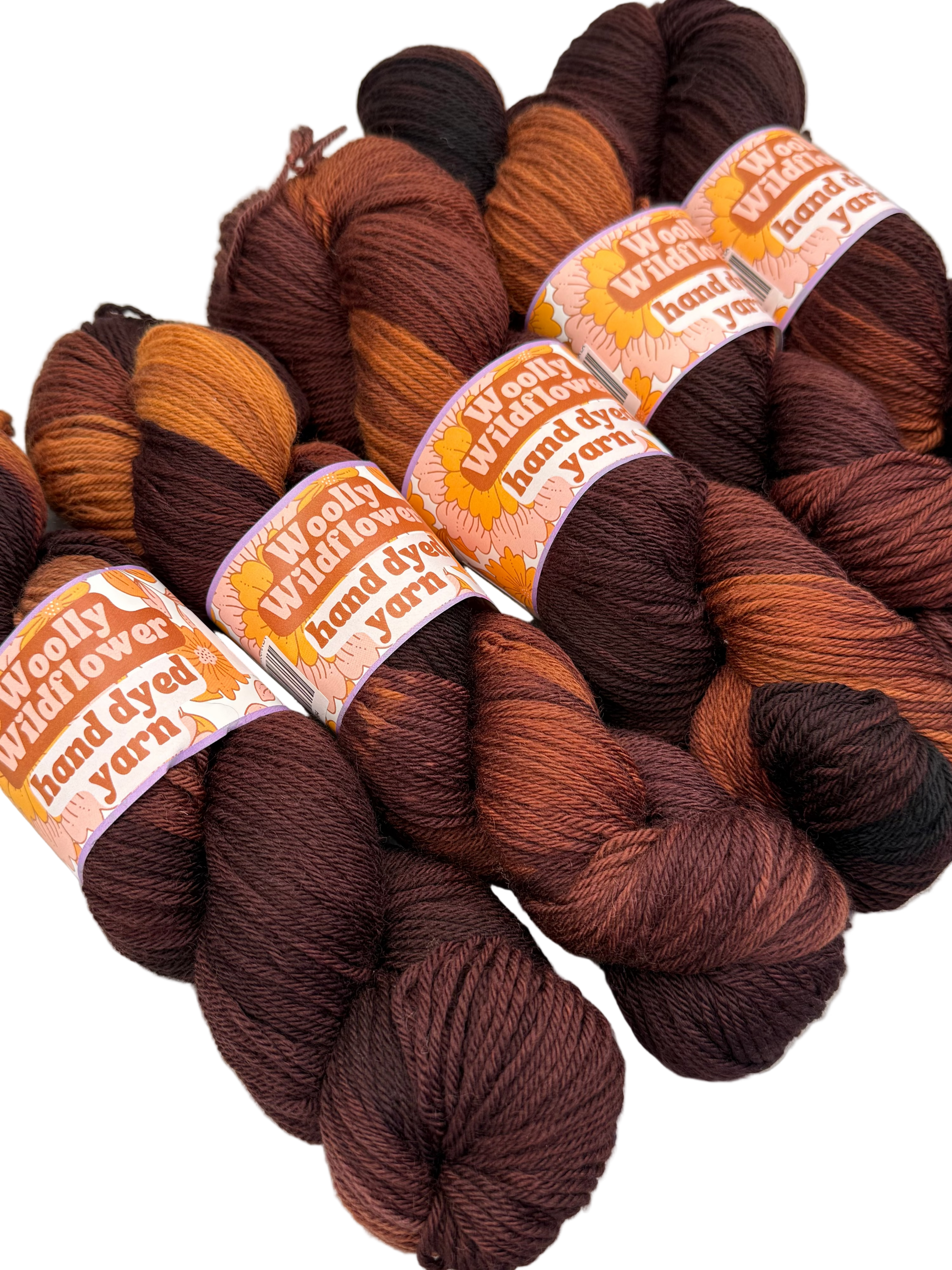Bundles of brown and orange yarn with 'Woolly Wildflower' labels on a white background
