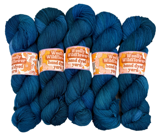 Five skeins of blue yarn with 'Woolly Wildflower' labels on a white background