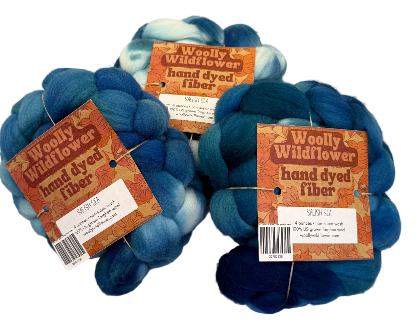 Three balls of blue and greens fiber with 'Woolly Wildflower' labels on a light gray background