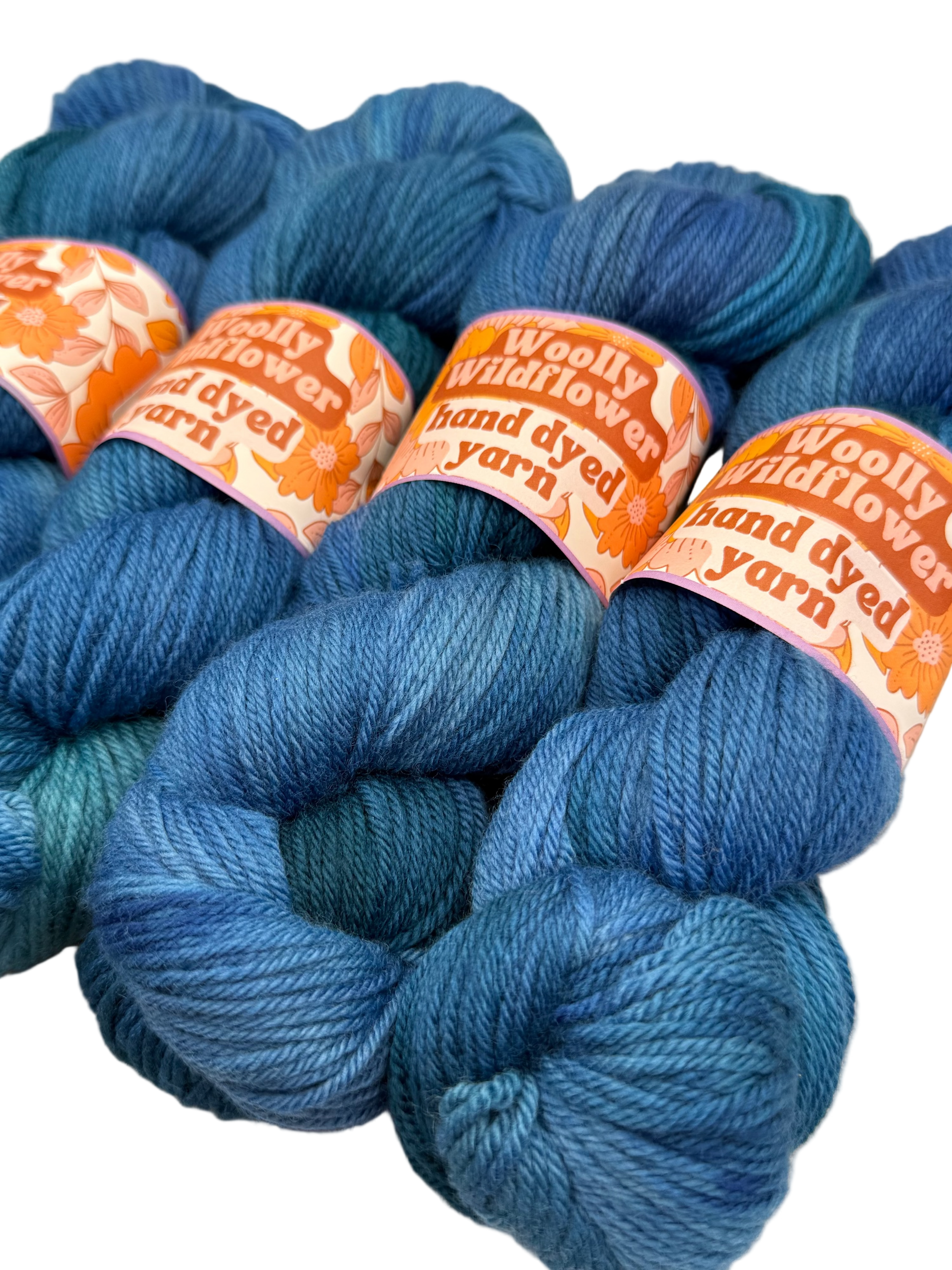 Blue yarn skeins with 'Woolly Wildflower' labels on a light background