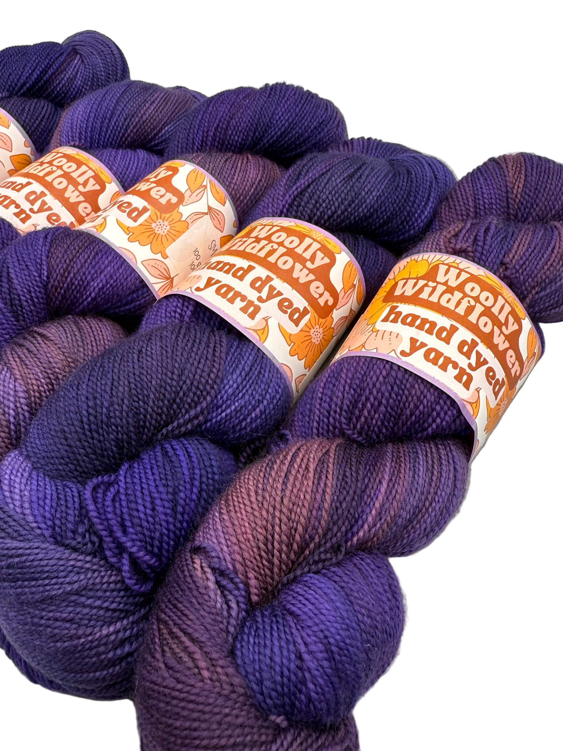 Purple yarn skeins with 'Woolly Wildflower Yarn' labels on a light gray background