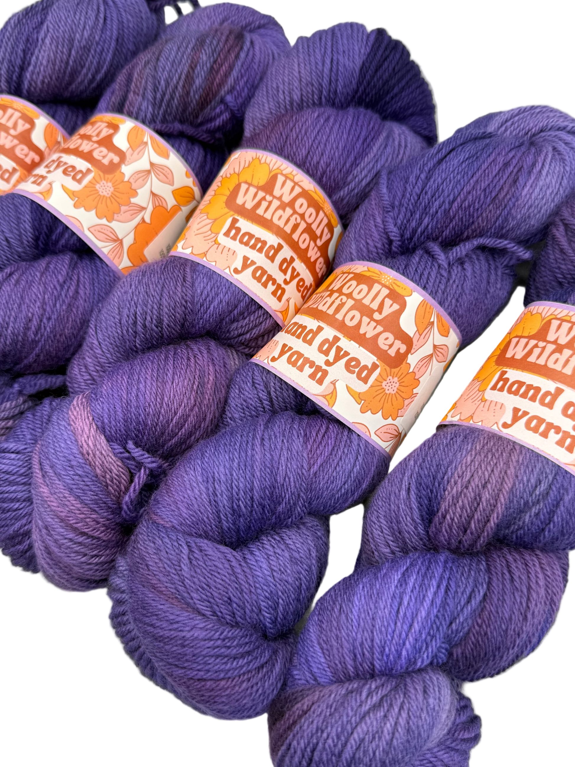 Purple yarn skeins with 'Woolly Flower' labels on a white background