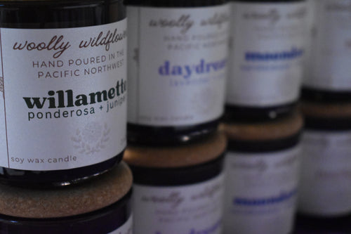 Candle jars with labels on a reflective surface