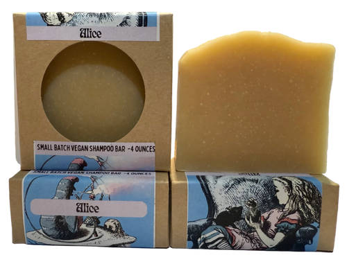 Three small batch vegan shampoo bars with decorative boxes on a table.