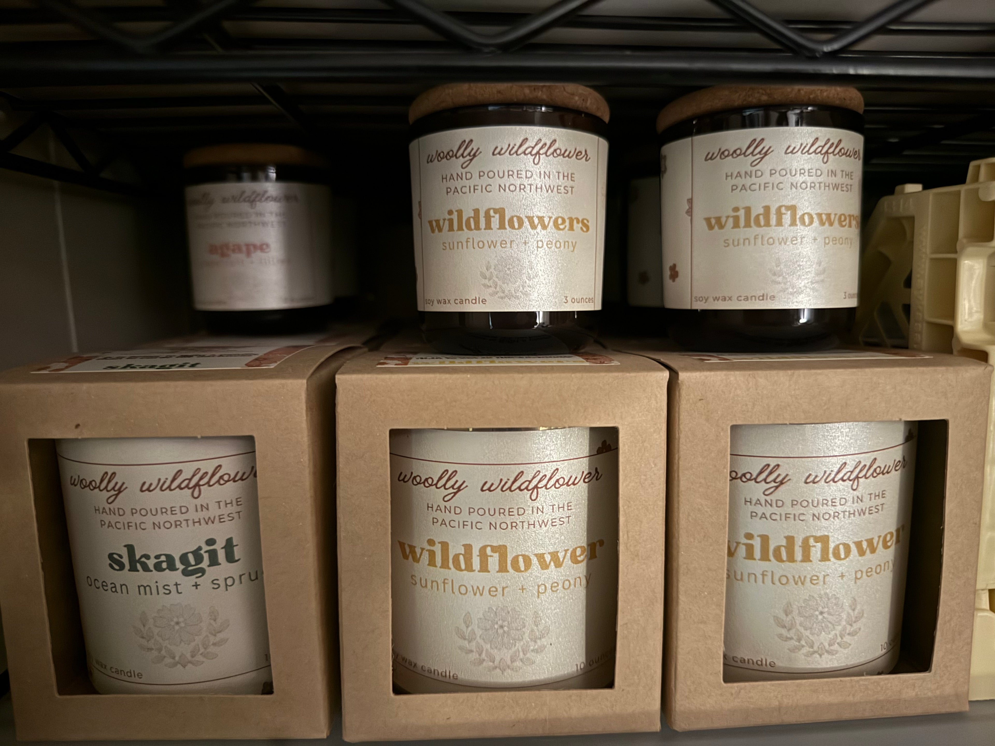 Jars of 'woolly wildflower' candles on a shelf with visible branding.