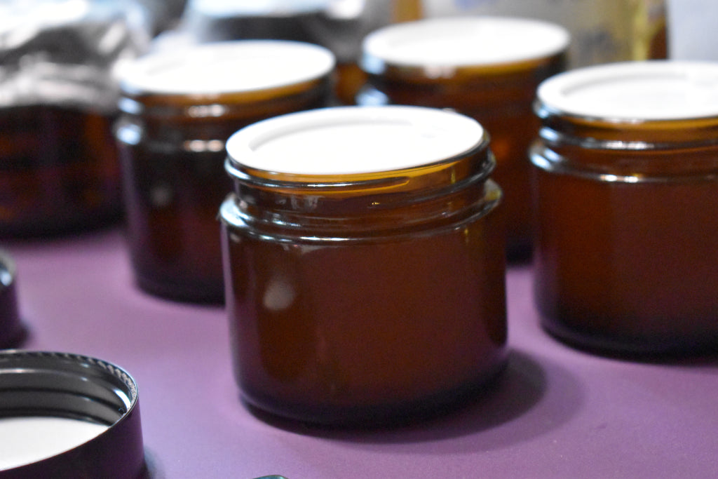 Brown glass jars with white lids on a purple surface