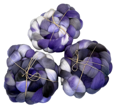 Three skeins of purple and white fibers on a light gray background
