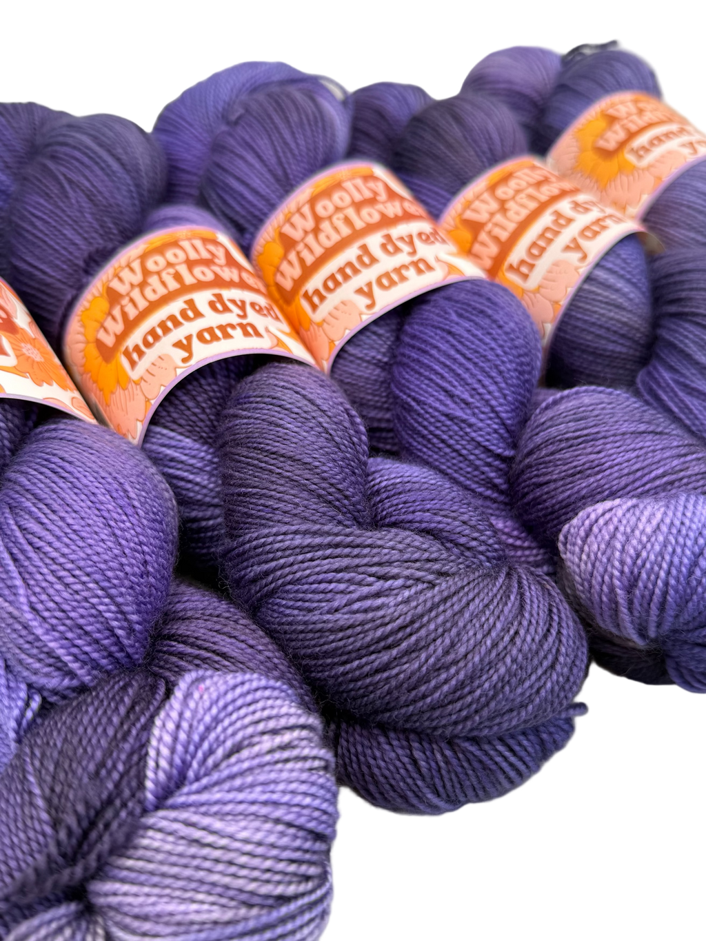 Purple yarn skeins with 'Woolly Wildflower' labels on a white background