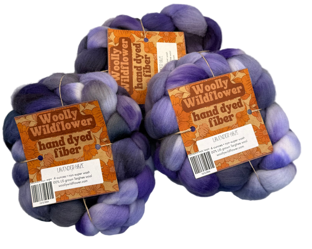 Three skeins of purple and gray hand-dyed fiber with 'Woolly Wildflower' labels on a gray background.