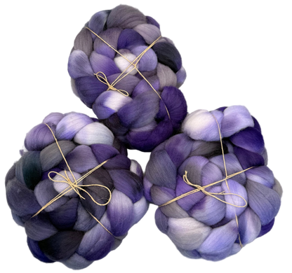 Three skeins of purple and gray fibers tied with twine on a light background
