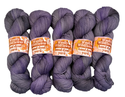 Five skeins of purple yarn with orange labels on a white background