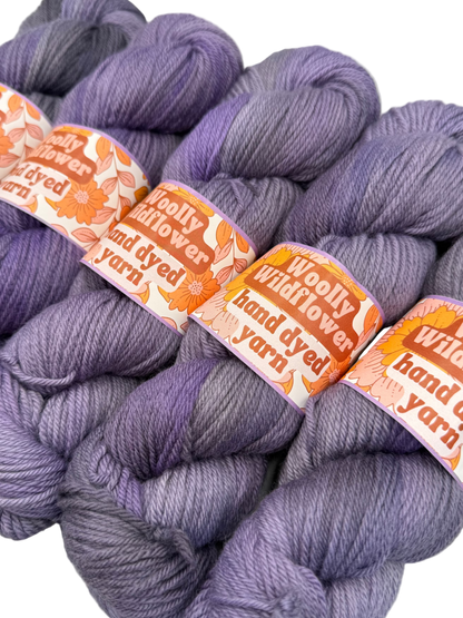 Bundles of purple yarn with 'Woolly Wildflower' labels on a white background