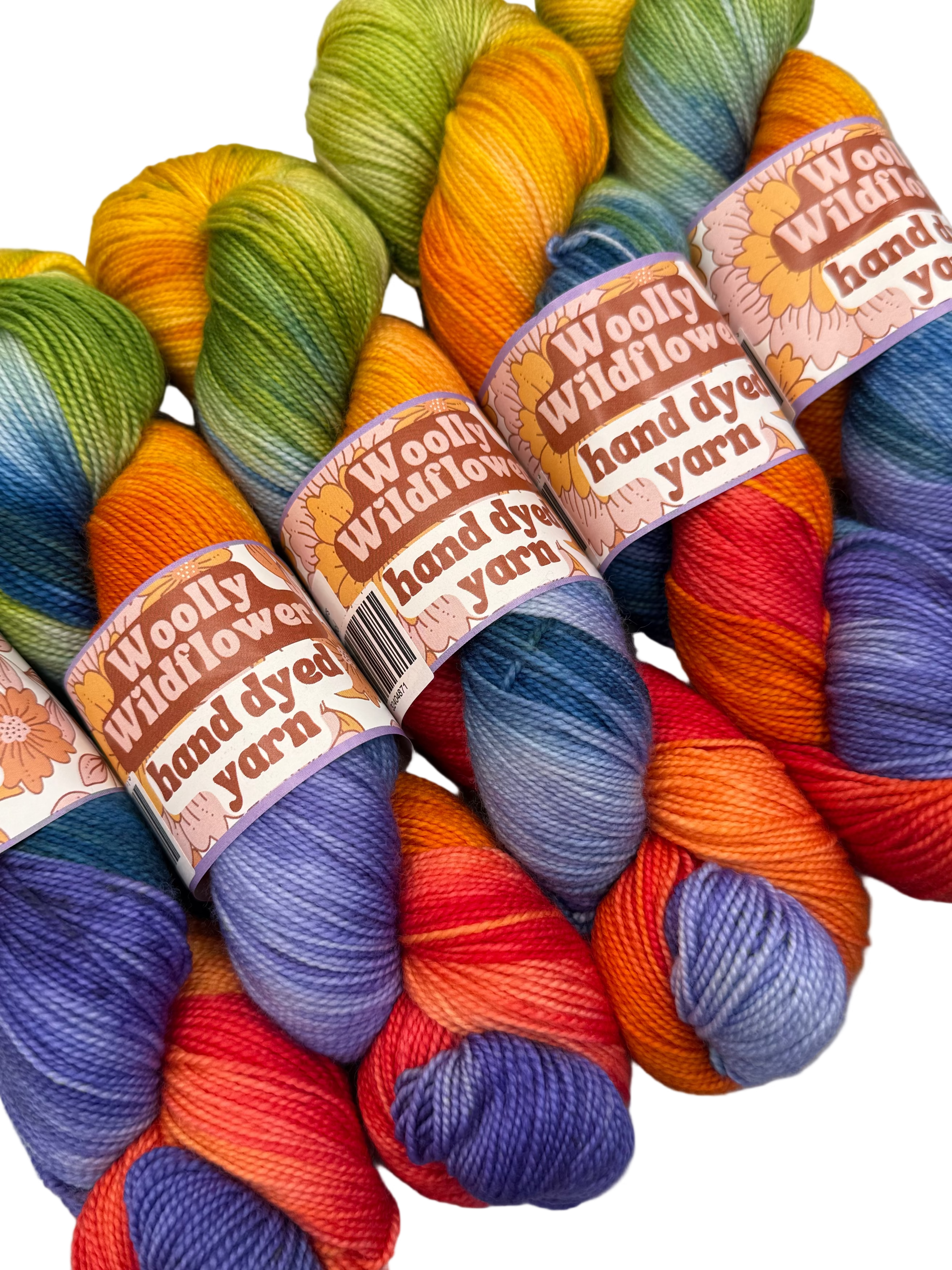 Colorful hand-dyed yarn with 'Woolly Wildflower' labels on a light gray background