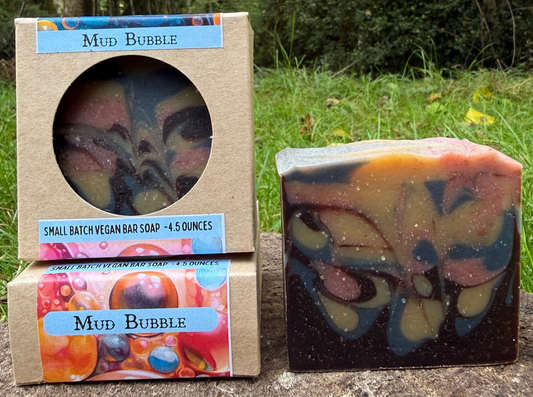 Mud Bubble soap bar and packaging in a natural setting with trees and grass.