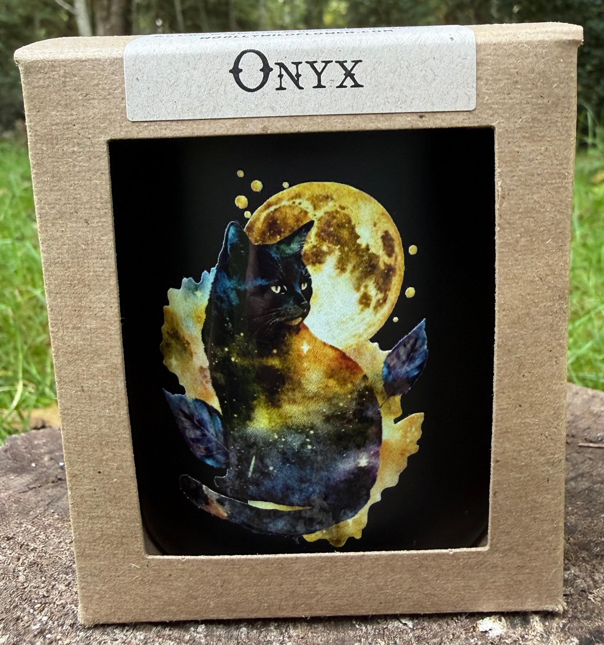 candle with decoration of a black cat with a moon in a natural setting