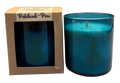 teal glass candle with tree design in a brown box labeled 'Patchouli + Pine'  on a white background