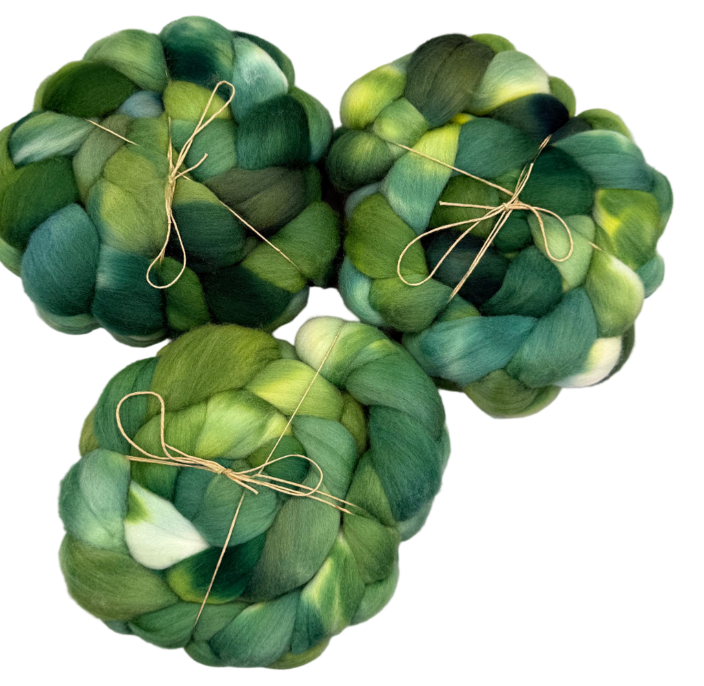 Three green skeins of fibers  tied together on a light gray background