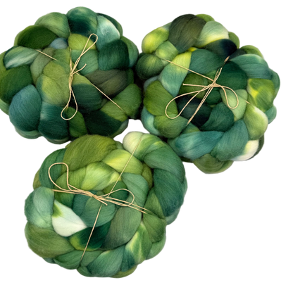Three green skeins of fibers  tied together on a light gray background