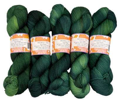 Five skeins of green yarn with labels on a white background