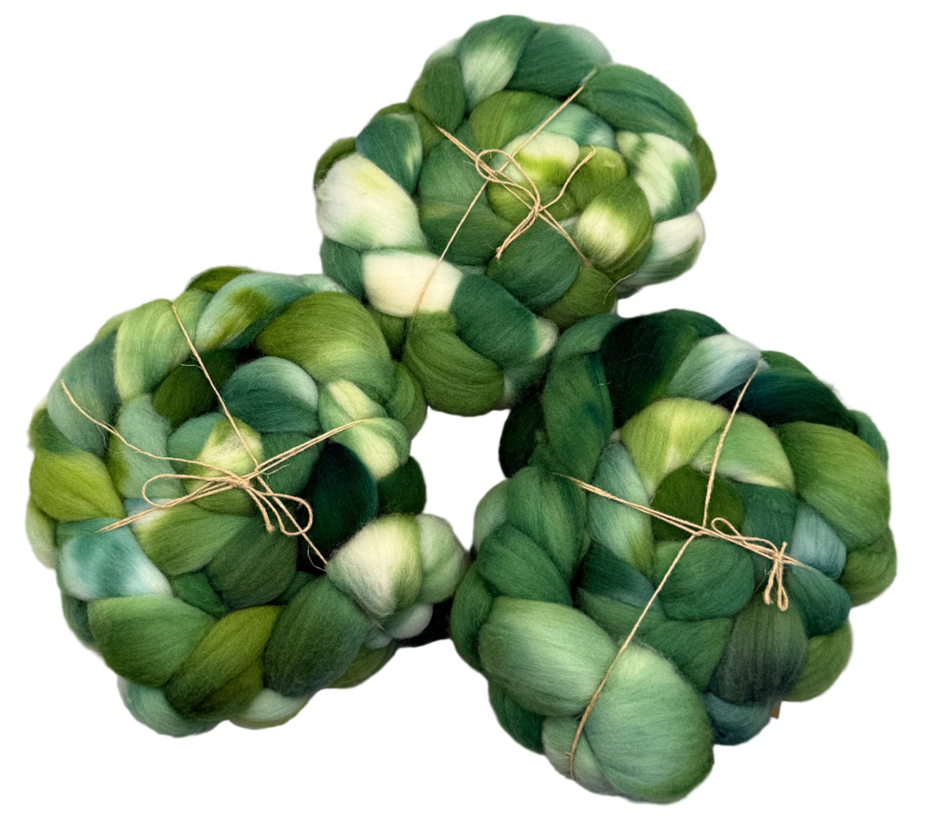 Three skeins of green fibers tied together on a light gray background