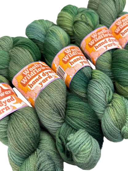 Green yarn skeins with 'Woolly Wormhead' labels on a white background