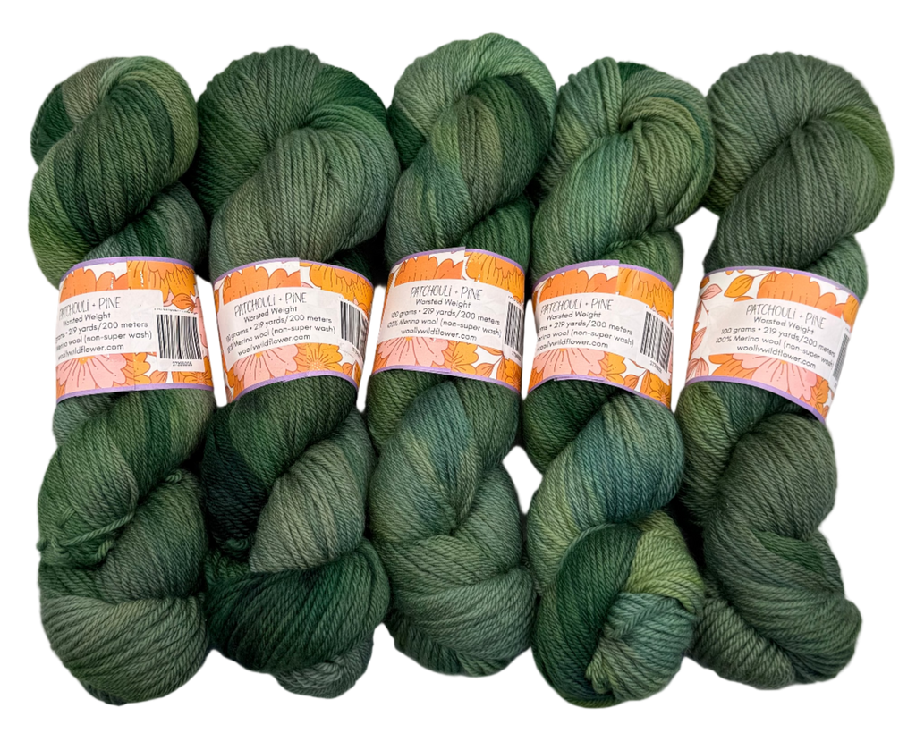 Five skeins of green yarn with labels on a gray background