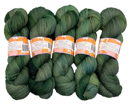 Five skeins of green yarn with labels on a gray background