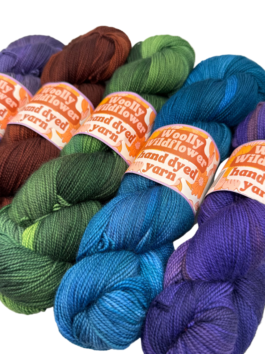 Bundles of colorful hand-dyed yarn with 'Woolly Wildflower' labels on a white background.