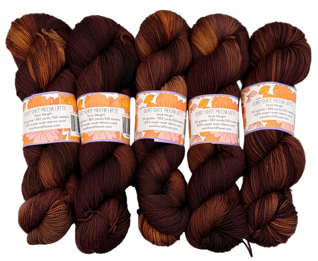 Five skeins of brown yarn with lighter brown accents on a light gray background