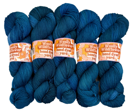 Five skeins of blue yarn with 'Woolly Wildflower' labels on a white background