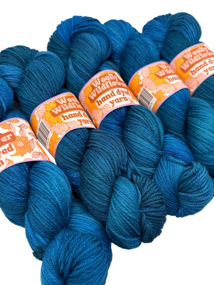Blue yarn skeins with 'Woolly Willows' labels on a white background