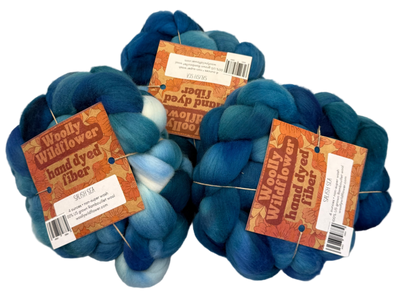 Three skeins of blue fiber with labels on a gray background
