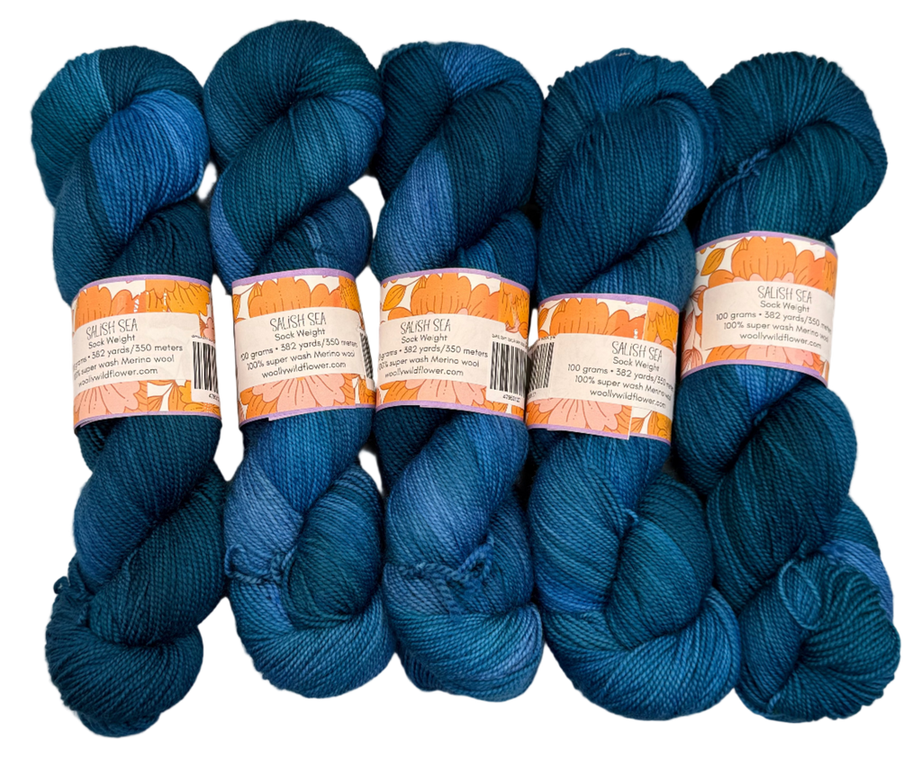 Five skeins of blue yarn with labels on a light gray background
