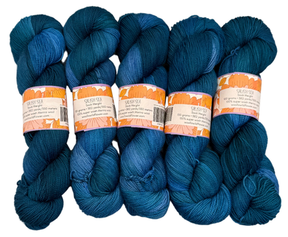 Five skeins of blue yarn with labels on a light gray background