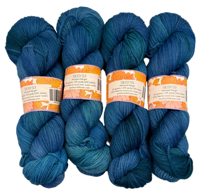 Five skeins of blue yarn with labels on a light gray background