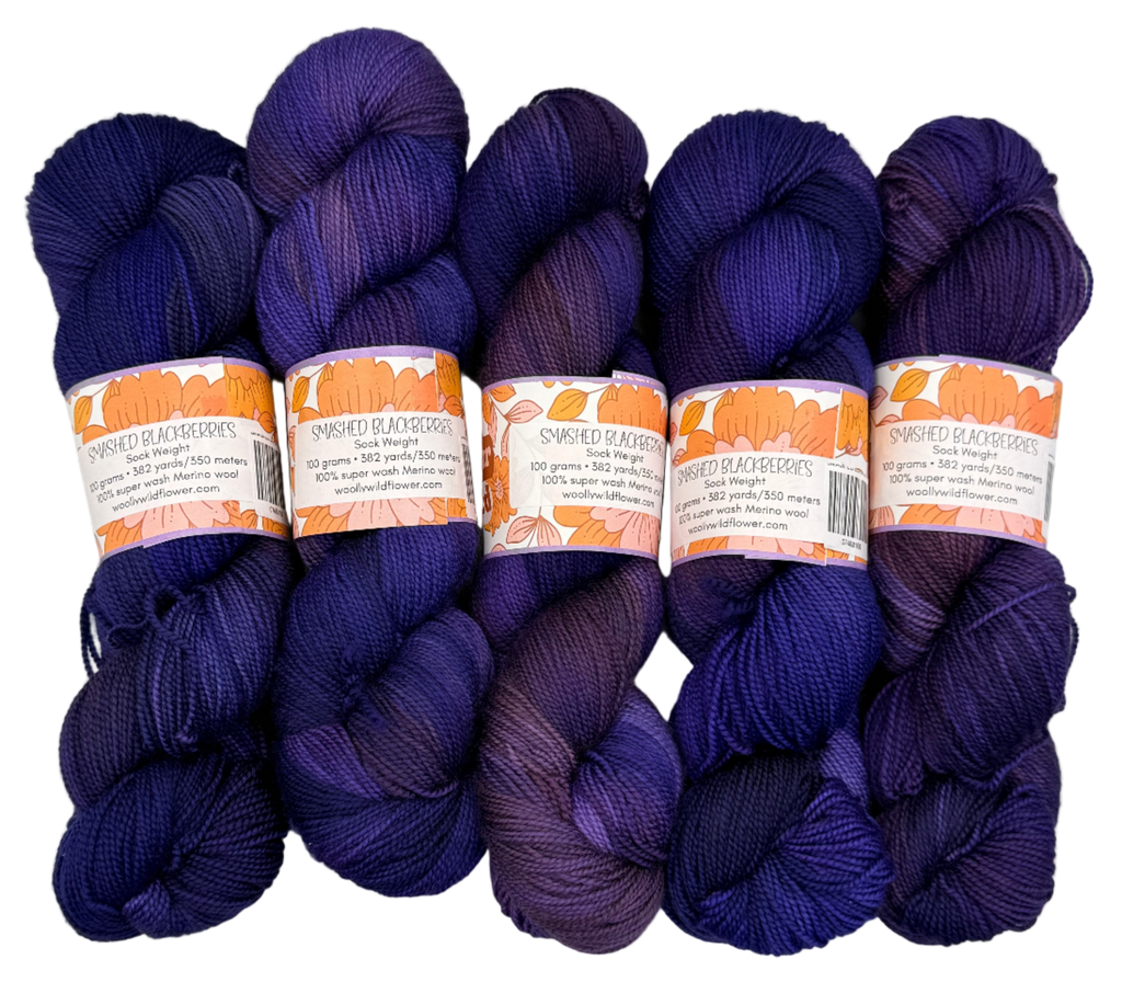 Five skeins of purple yarn with labels on a light gray background