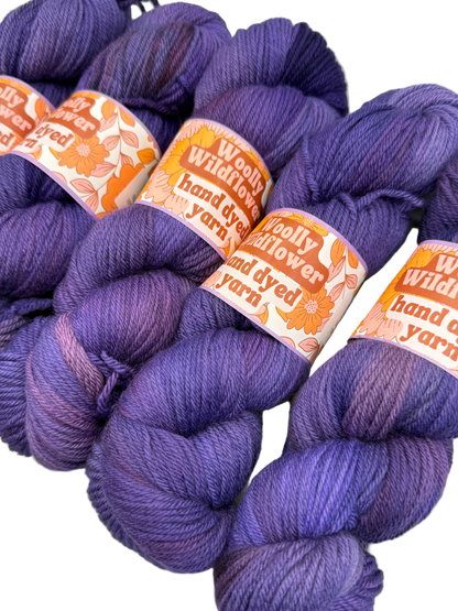 Purple yarn skeins with 'Woolly Flower' labels on a white background