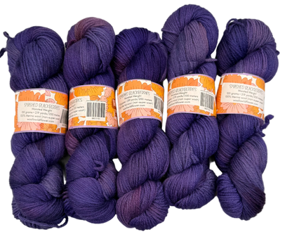 Five skeins of purple yarn with labels on a light gray background