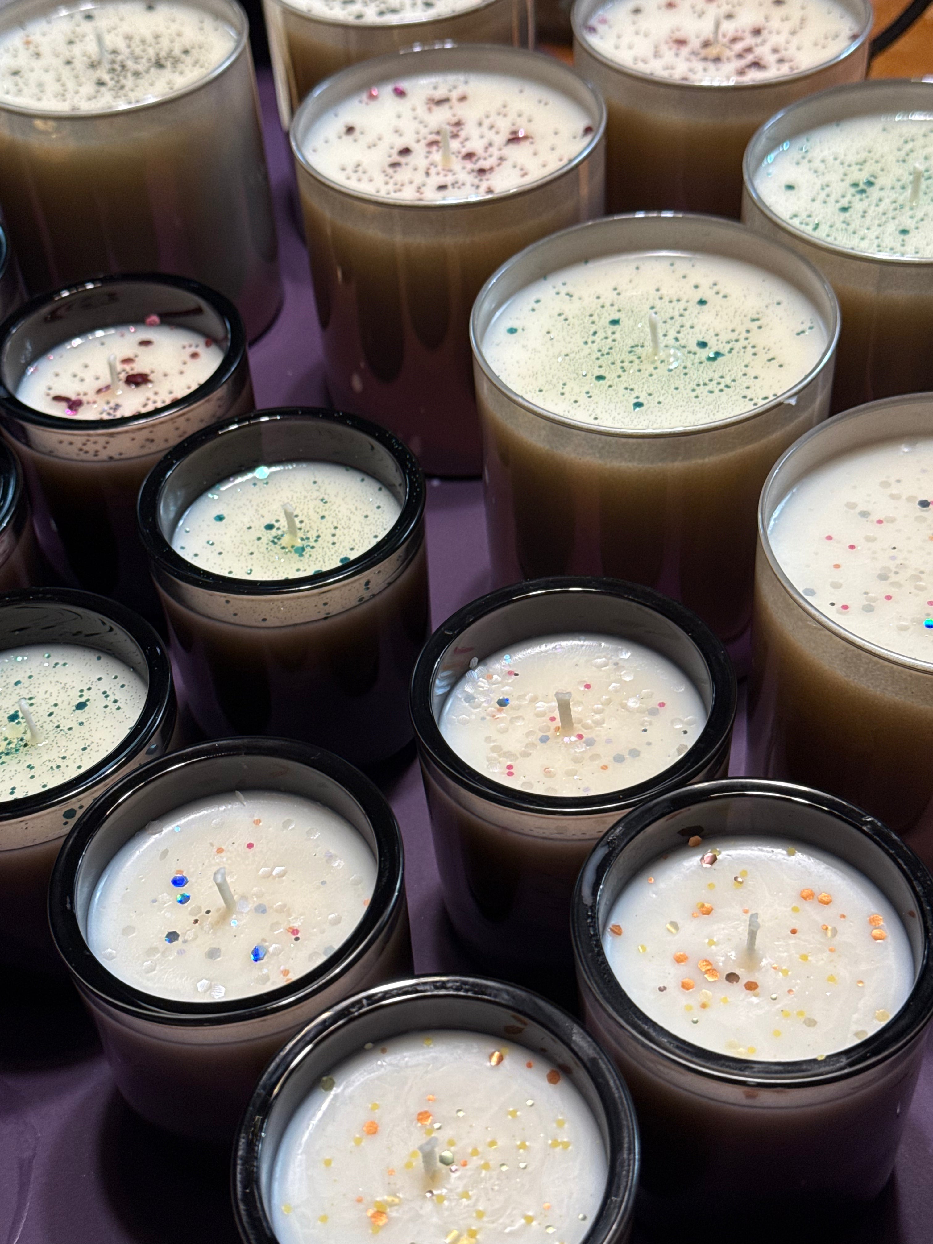 Multiple small candles with decorative toppings arranged on a purple surface.