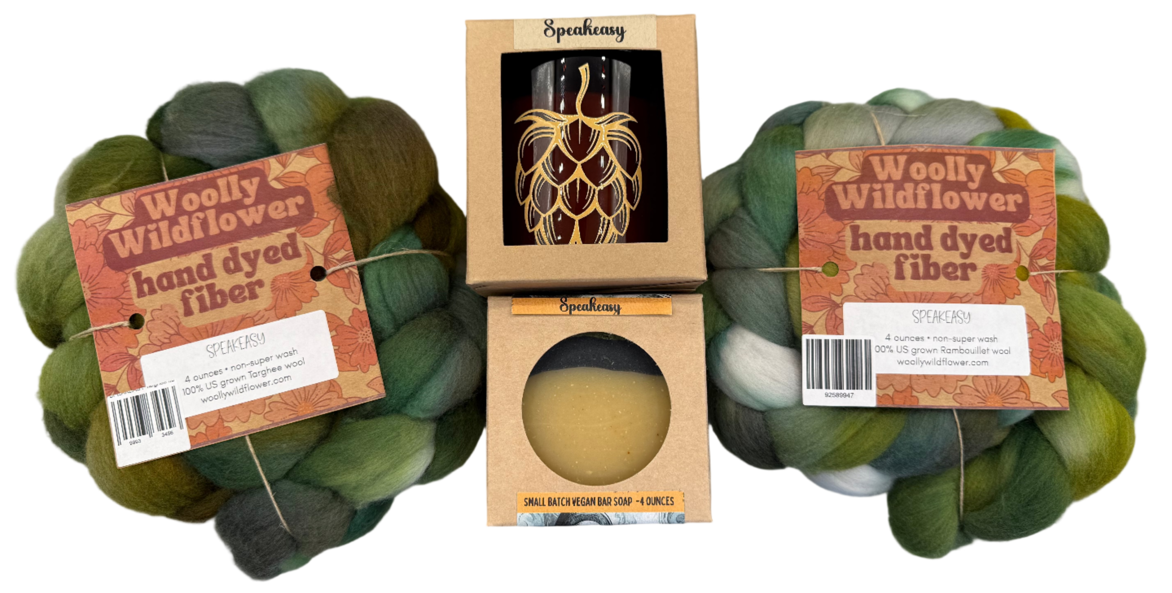Two skeins of green hand-dyed fiber with Speakeasy packaging on a gray background