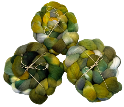 Three skeins of green and yellow fibers tied with twine on a white background